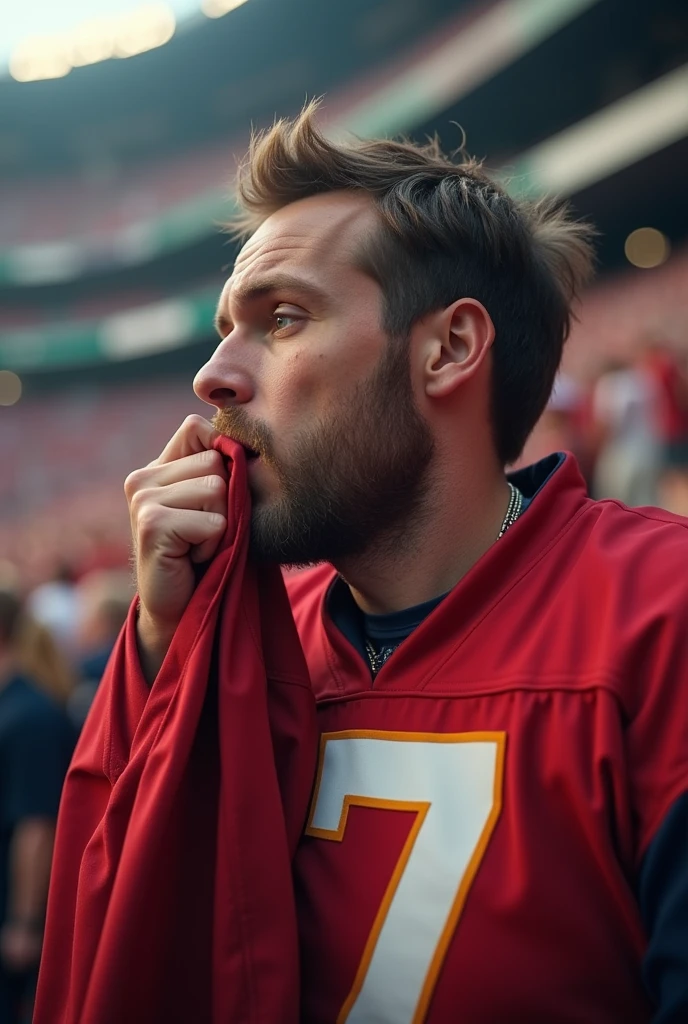 American football fan at the stadium, focused and kissing his team's shirt