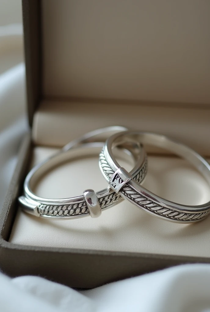 Two silver bracelets in a box, one with the legend "Harry" engraved y otro con la leyenda "What" engraved