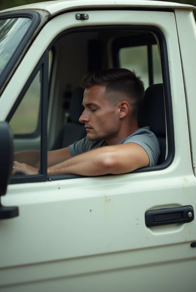 Un homme blanc avec des cheveux tres court en brosses,qui dort dans un vehicule blanc un dacia pick-up