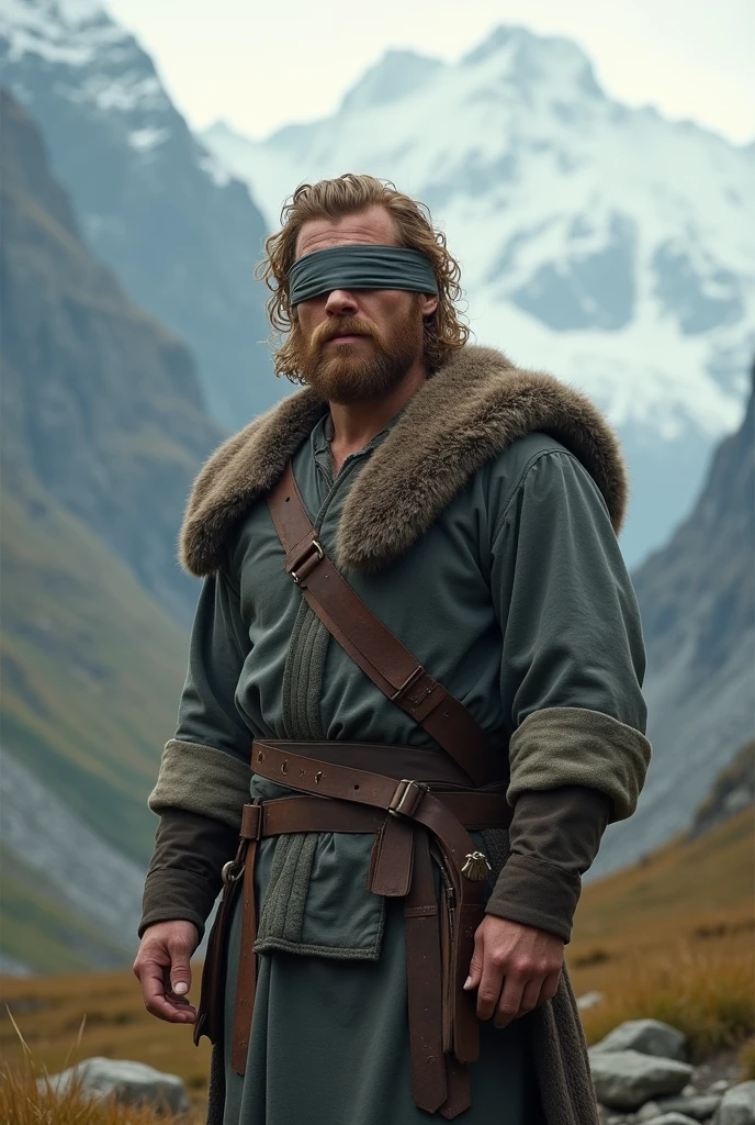 There is a man standing in a mountainous area. He is quite masculine, and has medium shoulder length hair. His hair is thick and dark blonde, having a waviness to it and curls at the base of the neck. The top of the hair goes down to his mouth, and the back goes down just past the base of his neck. He has a trimmed beard, and a grey blindfold covering his eyes. He also wears simplistic medieval clothing, looking somewhat like a Viking, short hair, short bear