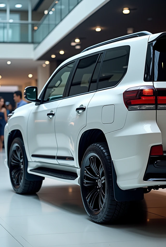 "A luxurious white Toyota land cruiser SUV with a modern design, viewed from the back side, in a bright and polished showroom. The vehicle features sleek tail lights with a futuristic design, a prominent rear bumper, and large black alloy wheels. The SUV's rear has a smooth and aerodynamic shape, with subtle curves and lines enhancing its appearance. The setting includes a glossy showroom floor reflecting the vehicle's details. In the background, a few people can be seen, adding to the busy and upscale showroom atmosphere. Lighting highlights the car’s glossy white paint and the dark accents on its rear."back side view