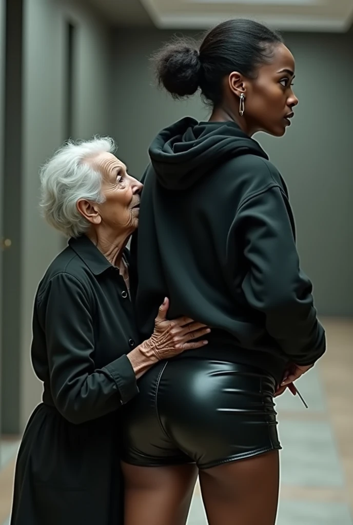 black woman hair in a bun black hoodie black leather short shorts rea;;y in shock as a old grandma in a dress on her knees kissing her ass behind her hand is in her ass holding her ass
