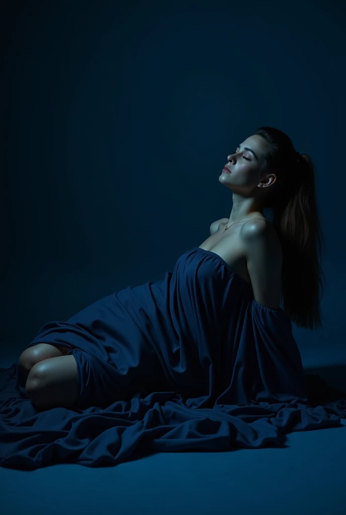 Woman lying on the floor covered with dark blue cloth, with dark blue background