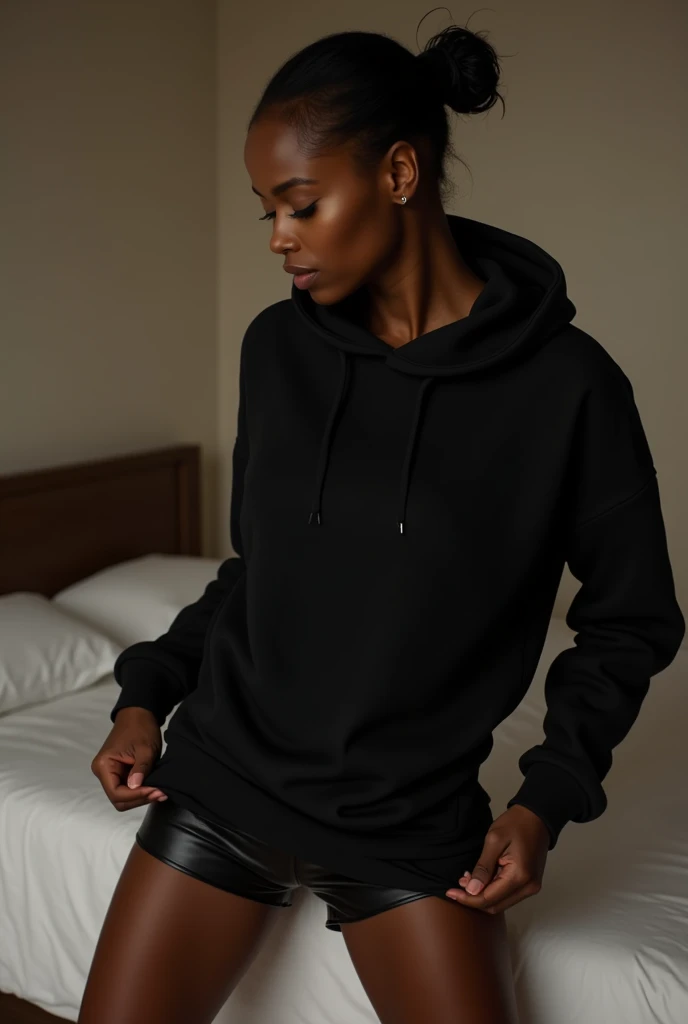 a black woman with her hair in a bun, wearing a black hoodie, bending over and pulling up her black leather short shorts, in her bedroom getting dressed