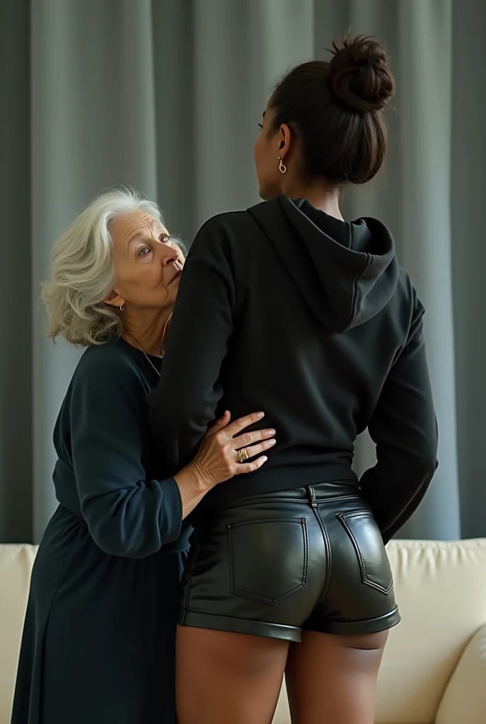 black woman hair in a bun black hoodie black leather short shorts getting fucked in the ass by a old ugly woman in a blue dress in a living room