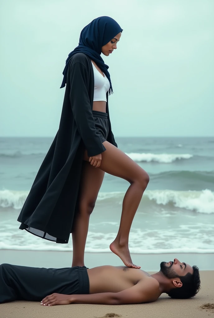 Navy blue headscarf on the beach, Black long coat, barelegged, white shirt, skinny woman. Man lying in front of woman. Woman puts her foot on the front of man's sweatpants.