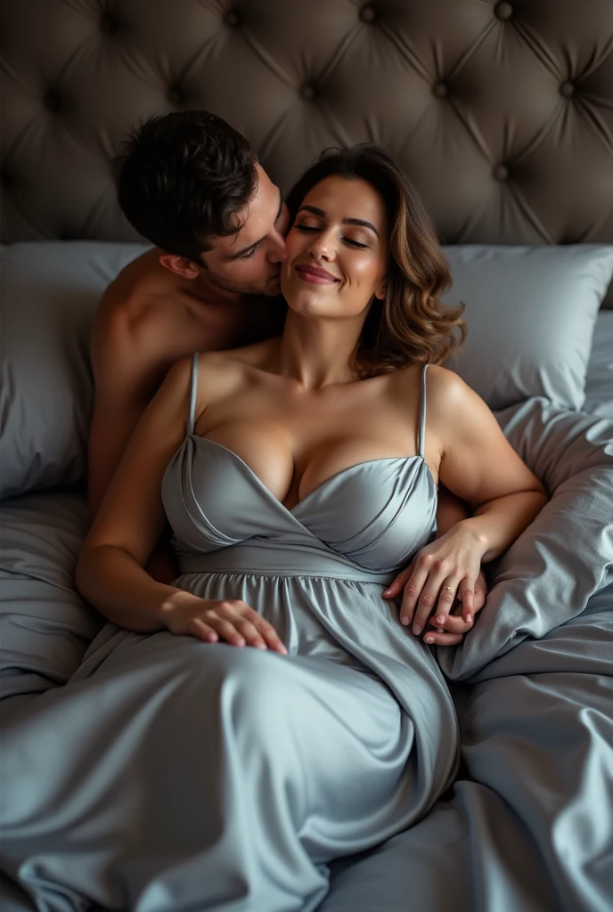 Russian milf with big boobs wearing silk satin dress maxi lying on a wedding bed with king size silk duvet in grey color kissed on neck by a man from behind