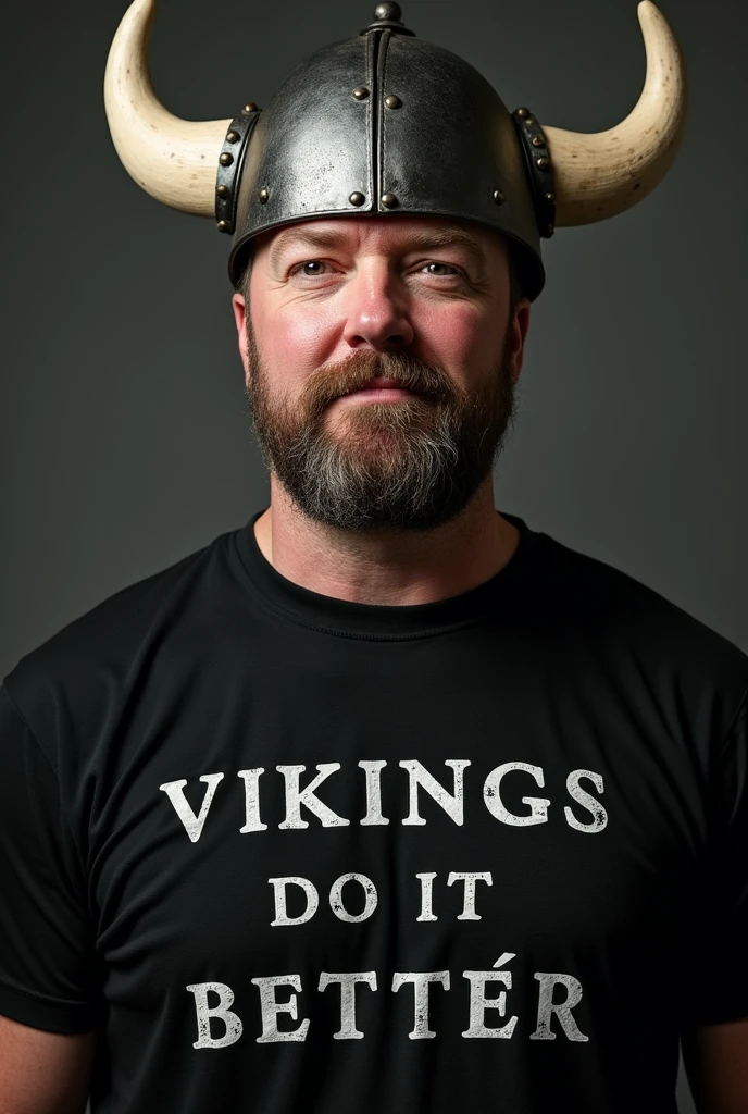 Ricky Gervais wearing a black shirt and black pants and black boots and wearing a shirt with that reads Vikings Do It Better Close up no beard and mustace with short hair and Viking hat