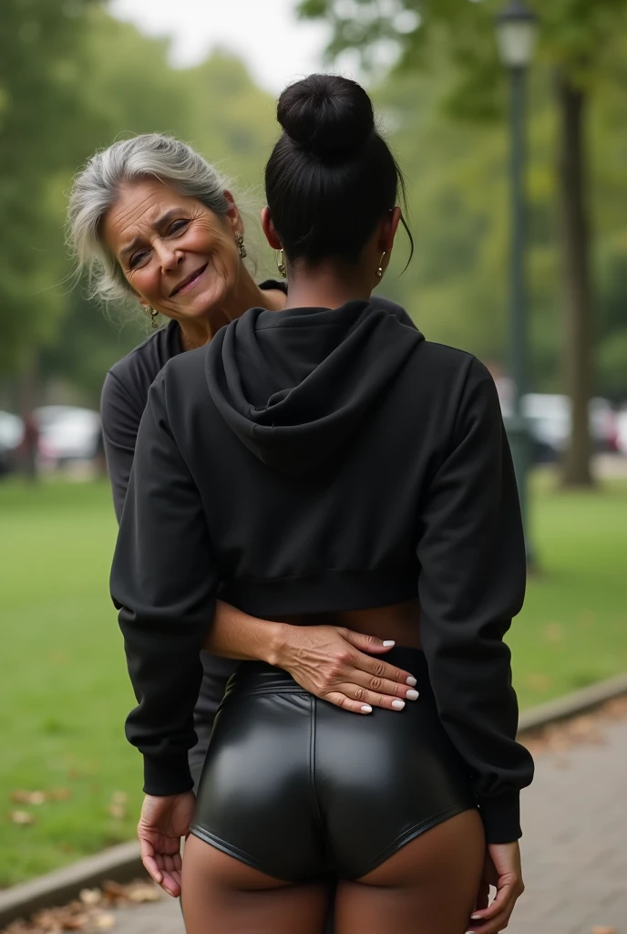 black woman hair in a bun black hoodie black leather short shorts bending over getting fucked in the ass by a old ugly woman in a dress in a park
