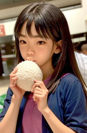 A girl holding a rice ball close to her mouth