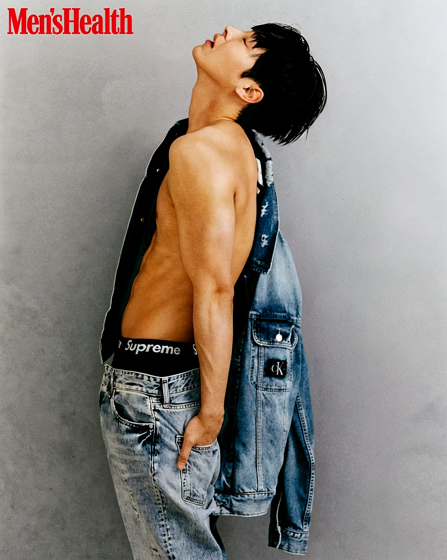 a asian man, model, platinum medium hair falling loosely and naturally over his face with soft waves, has visible freckles on nose andcheckbones, fair shaved skin, dark and expressive eyes, and natural lips, shooting to a fashion editorial of Calvin Klein Jeans