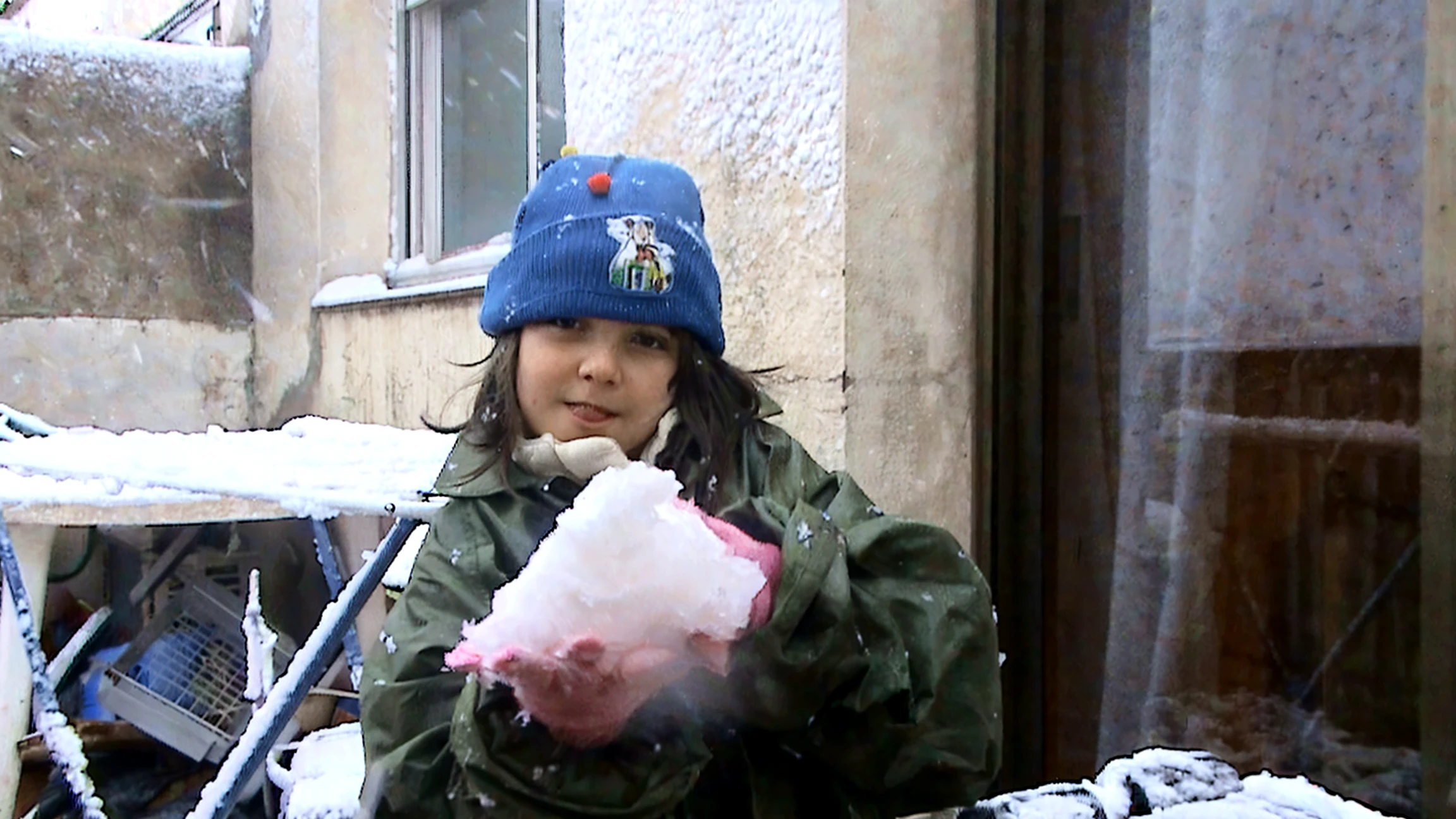 Palestinian smiling in the building ruins while touching water mellon