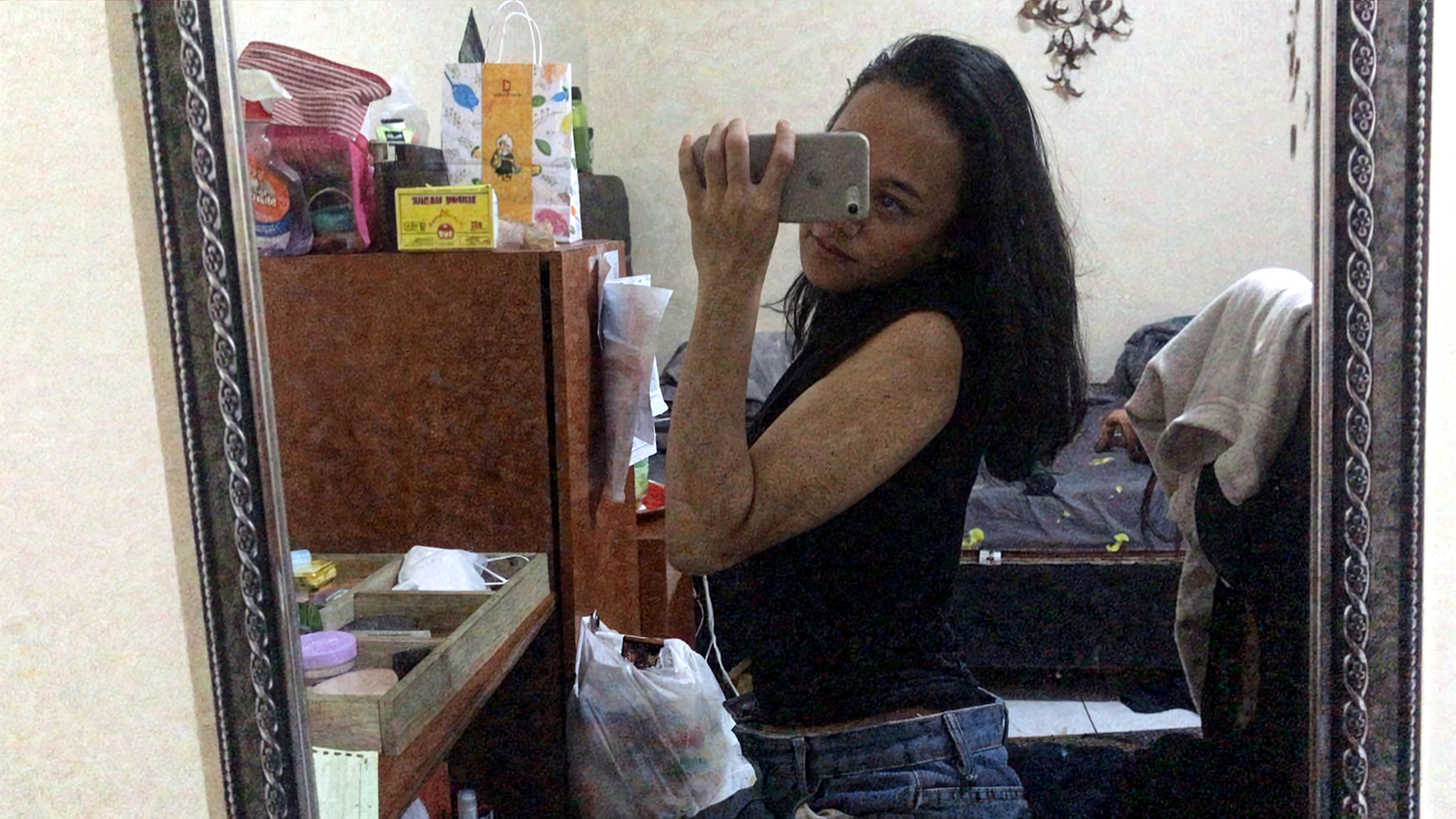 skinny 35 years old woman, FULL BODY, small ass, black long STRAIGHT hair, in a white background, black nails, triangular necklace, triangular earrings, TAKING A NUDE SELFIE showing vagina