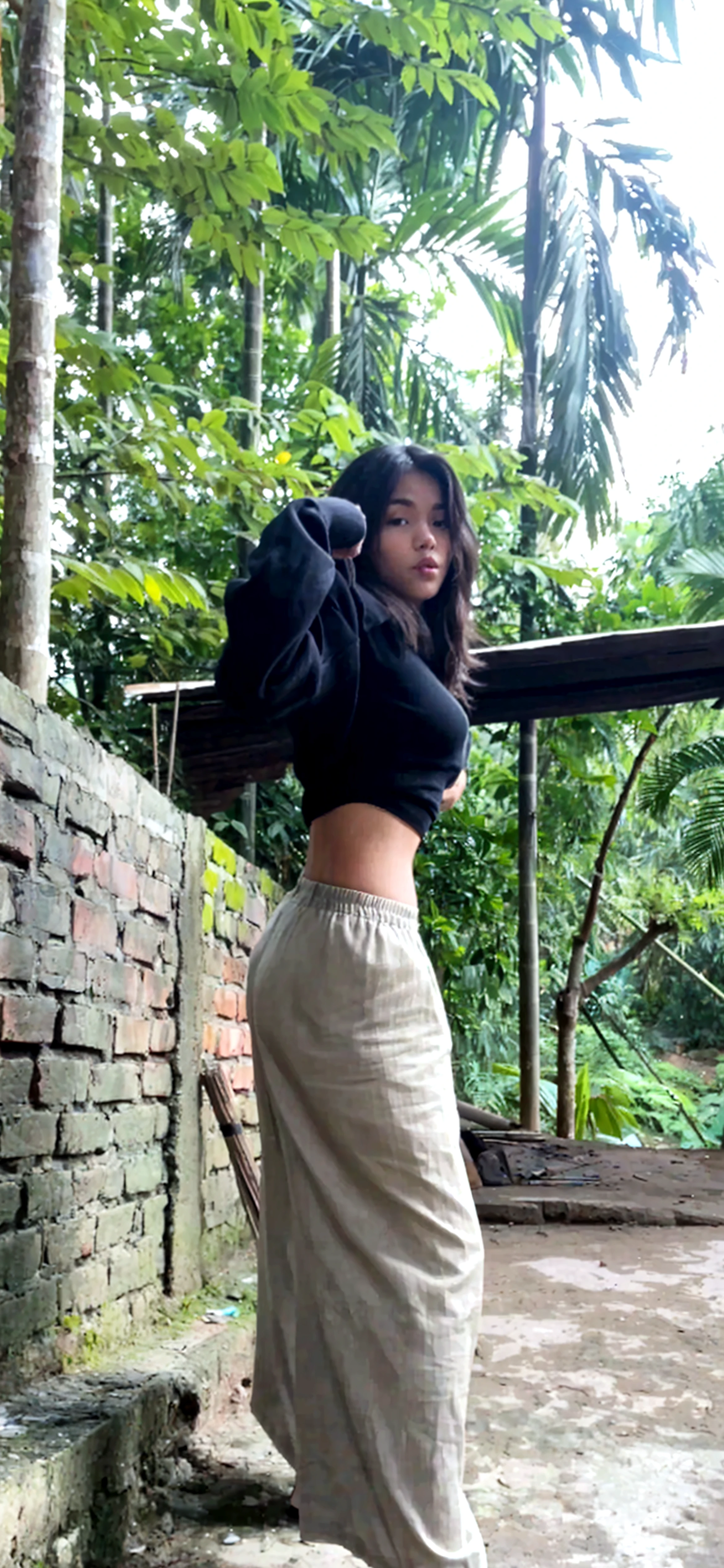 srilankan girl on a hotel balcony peeking the beautiful view, wearing a black tshirt and a grey trouser