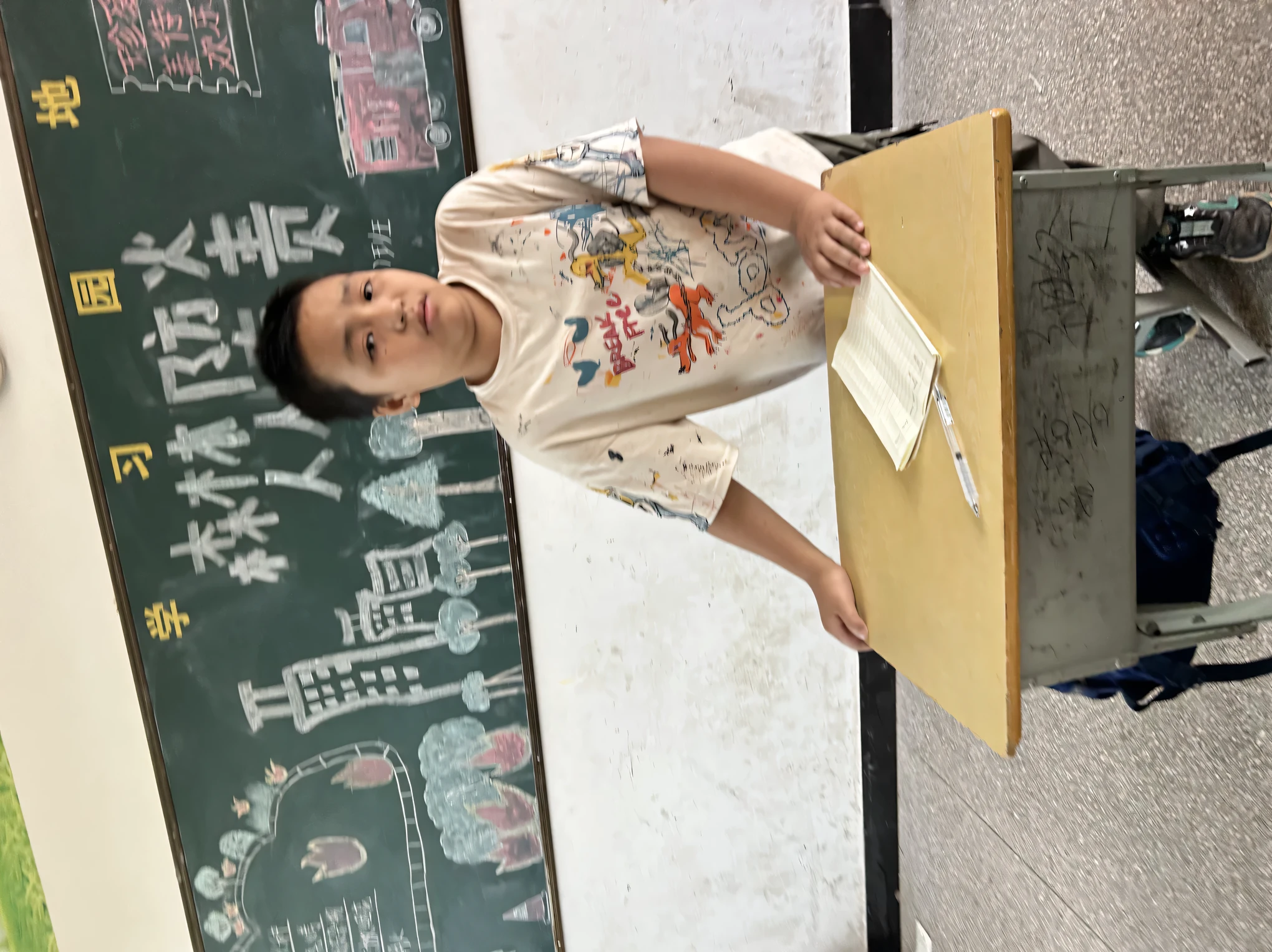 There was a little boy holding a sign in front of the blackboard,