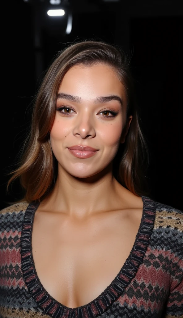 A closeup portrait photo of a woman with medium length hair who gazing directly at the camera with a neutral expression. She is wearing a multicolored knitted sweater against a dark background. Spotlight illumination.