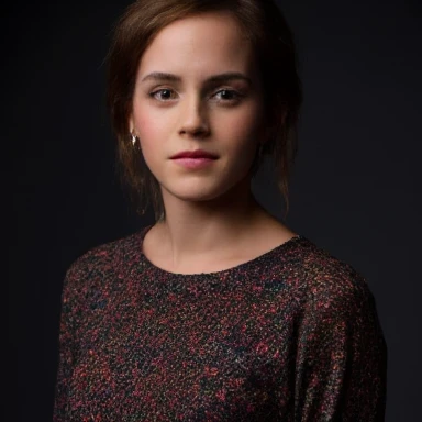 A closeup portrait photo of a woman with medium length hair who gazing directly at the camera with a neutral expression. She is wearing a multicolored knitted sweater against a dark background. Spotlight illumination. 
