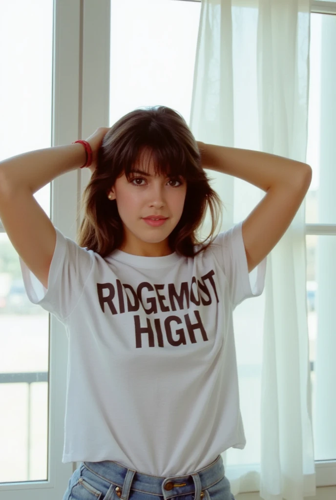 This film photograph captures a young woman named phoebe with fair skin and a slim physique. She has long, wavy brown hair that cascades down her back, partially pulled up with her hands behind her head. Her facial features are delicate, with high cheekbones, full lips, and a slightly rounded jawline. She has expressive brown eyes accentuated with subtle makeup, including a touch of pink lipstick and light eyeshadow. She is wearing a loose-fitting white t-shirt with a prominent bold text that reads "RIDGEMONT HIGH" centered on the chest, suggesting a casual outfit. The shirt appears to be made of soft, cotton fabric, and the texture of the material is visible, adding a sense of comfort and ease. The background features large, white-framed windows that allow natural light to flood the room, creating a bright and airy atmosphere. The windows are partially covered by sheer white curtains, adding a soft, diffused effect to the overall scene. The image is sharp and clear, with a focus on the subject, highlighting her youthful and confident demeanor. The overall aesthetic is modern and minimalistic, emphasizing the subject's natural beauty and the simplicity of the setting. 