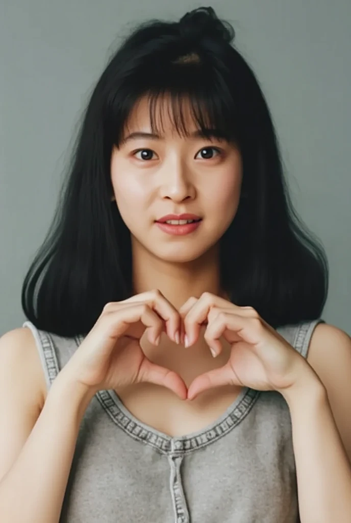 She is in a pose wearing a camisole, making a firm big heart shape with both hands, and holding it in front of her chest, View above collarbone、Throat up for a cute smile、Monotone background

