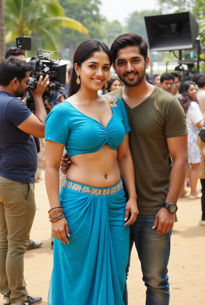 On a lively film set, an Indian girl stands confidently as the center of attention, with long hair styled in an elegant updo and a radiant smile directed at the camera. She is wearing a traditional blue blouse with short sleeves and a knotted front, paired with a matching blue draped bottom piece featuring an embellished waistband. Her midriff and navel are visible, emphasizing her toned waist and curvy figure. She wears traditional Indian jewelry, including gold dangling earrings and colorful bangles, with expressive eyes and a small bindi on her forehead. The girl is leaning on the shoulder of a man standing beside her on the set. Her arm is relaxed around his shoulder adding a sense of camaraderie. Around them, a camera crew is focused, and the director stands nearby, enthusiastically explaining the shot. The set is filled with film equipment, lighting rigs, and crew members, creating an energetic, vibrant atmosphere typical of a film production,sunny