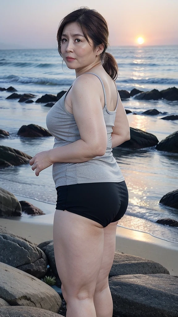 woman in a gray top and black shorts standing on a beach, standing at the beach, girl looking at the ocean waves, sport bra and dark blue shorts, looking at the ocean, seen from the back, next to the reflecting ocean, facing away from camera, at a beach, facing away from the camera, looking out at the ocean, shot from the back