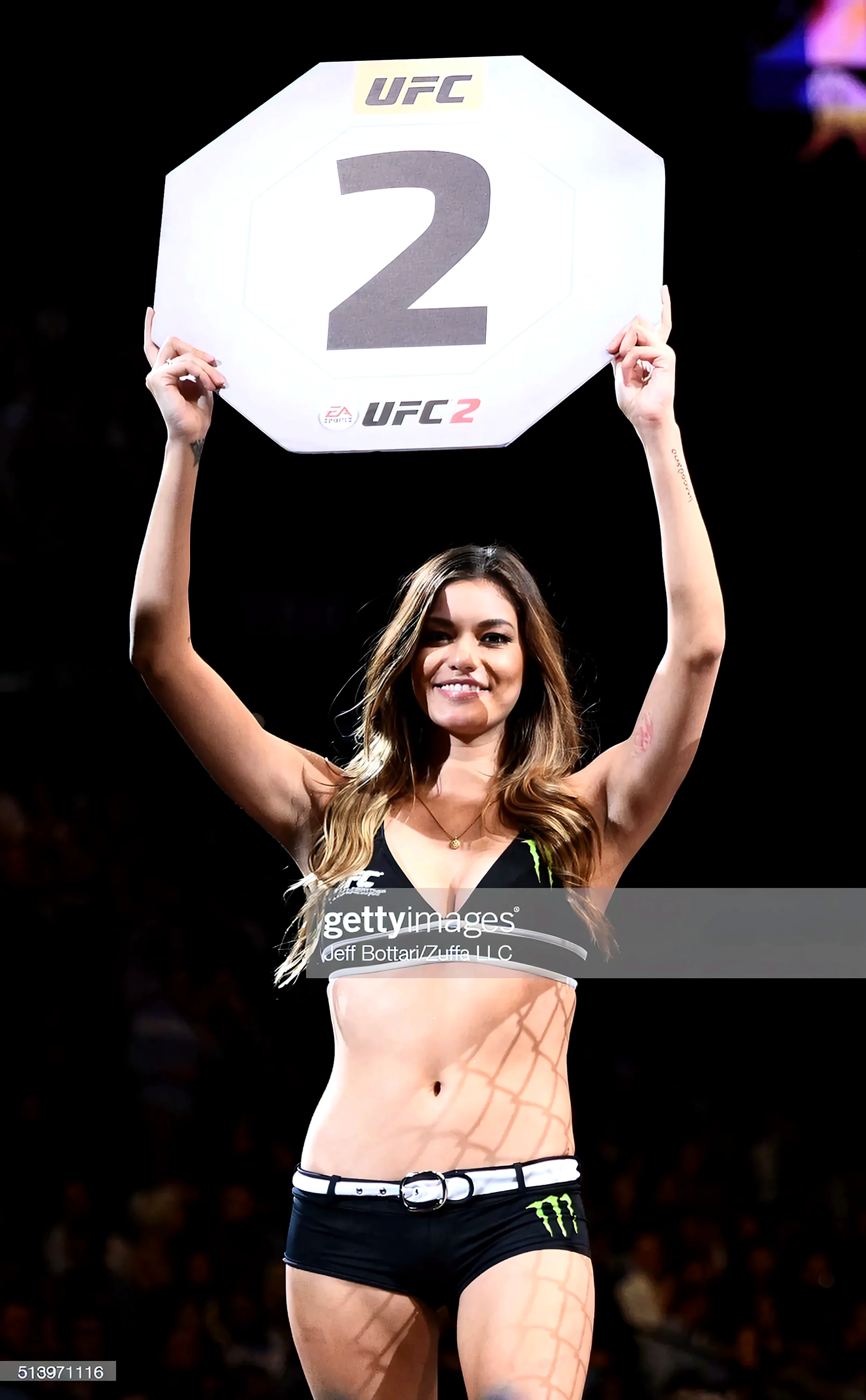 a photo of a blonde ring girl, holding a sign, (rnd1), UFC, at a fight, octagon, big tits, best quality, photorealistic, fine details <lora:r1ngg1rl:0.7>