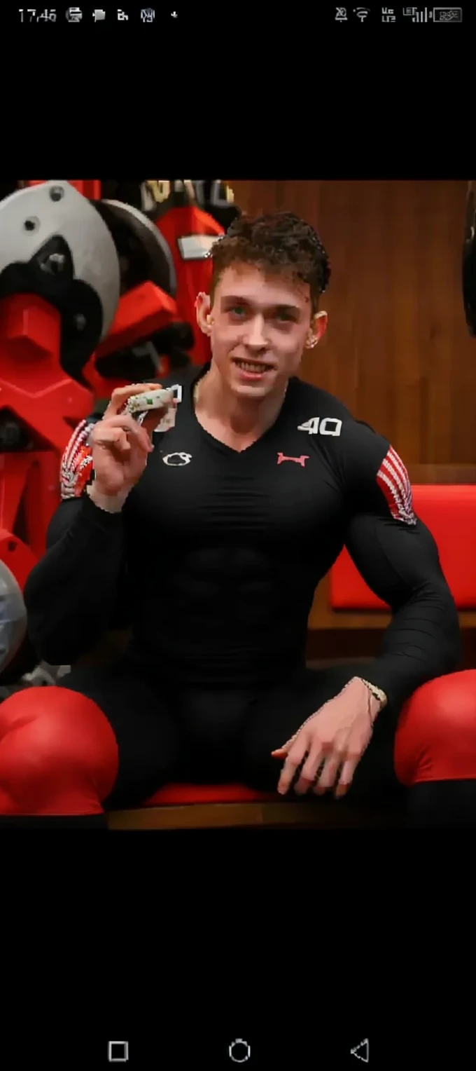 hot guy in a wrestling uniform. pale skin, oiled up, sexy redhead, skinny, good lighting, very pale skin, light skin, wrestling singlet, sitting on prison floor, body shot, wrestling spandex, bulge print, hot guy, mature face, irish, fully clothed, full singlet, long-seam singlet