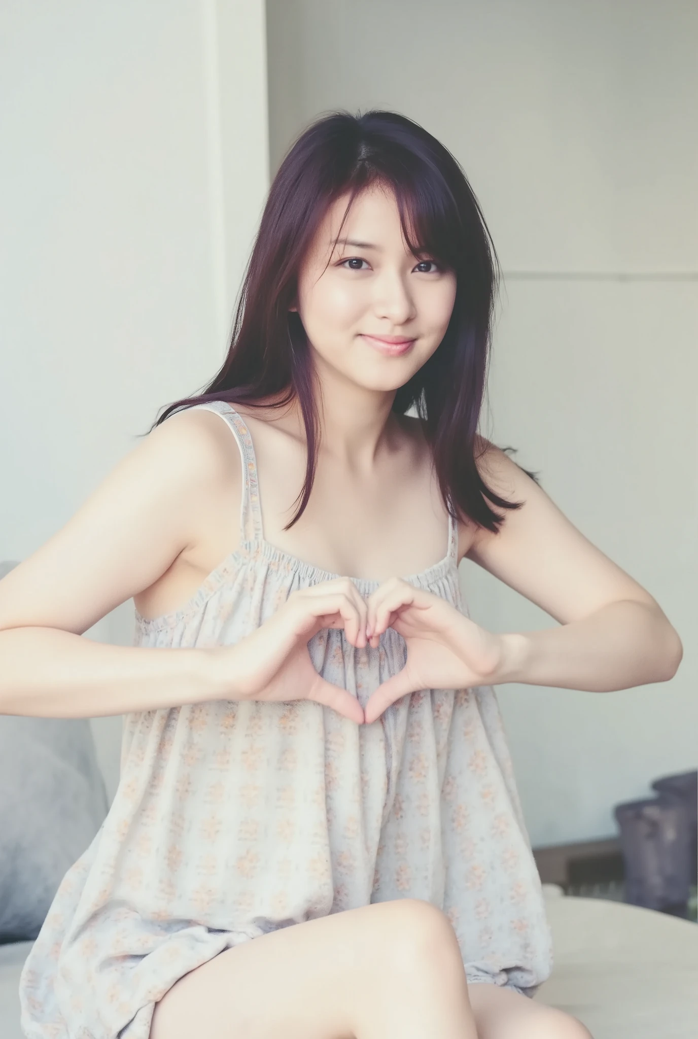 A smiling woman poses alone wearing off-the-shoulder pajamas in pastel colors that convey warmth simply by touching them softly and softly, making a firm, large heart shape with both hands, and holding them in front of her chest, View above collarbone、The background is a monotone 、
