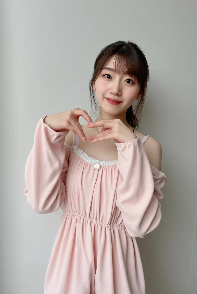 A smiling woman poses alone wearing off-the-shoulder pajamas in pastel colors that convey warmth simply by touching them softly and softly, making a firm, large heart shape with both hands, and holding them in front of her chest, View above collarbone、The background is a monotone 、
