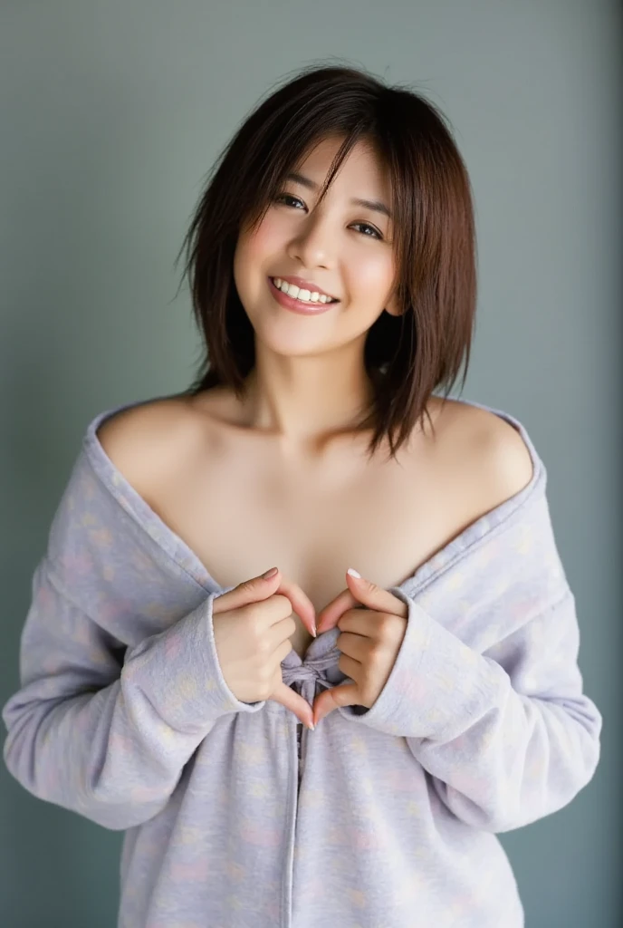 A smiling woman poses alone wearing off-the-shoulder pajamas in pastel colors that convey warmth simply by touching them softly and softly, making a firm, large heart shape with both hands, and holding them in front of her chest, View above collarbone、The background is a monotone 、
