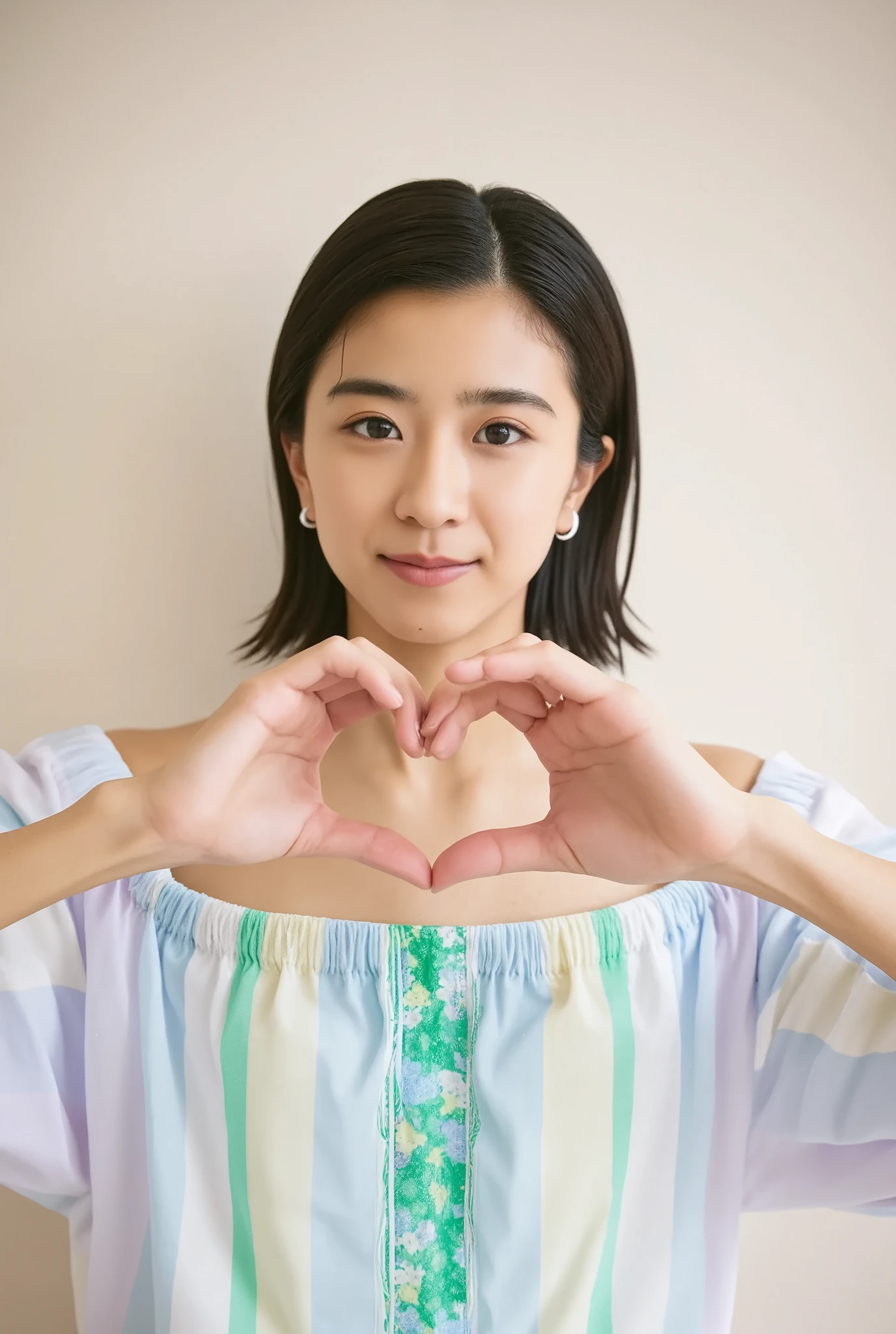 A smiling woman poses alone wearing off-the-shoulder pajamas in pastel colors that convey warmth simply by touching them softly and softly, making a firm, large heart shape with both hands, and holding them in front of her chest, View above collarbone、The background is a monotone 、
