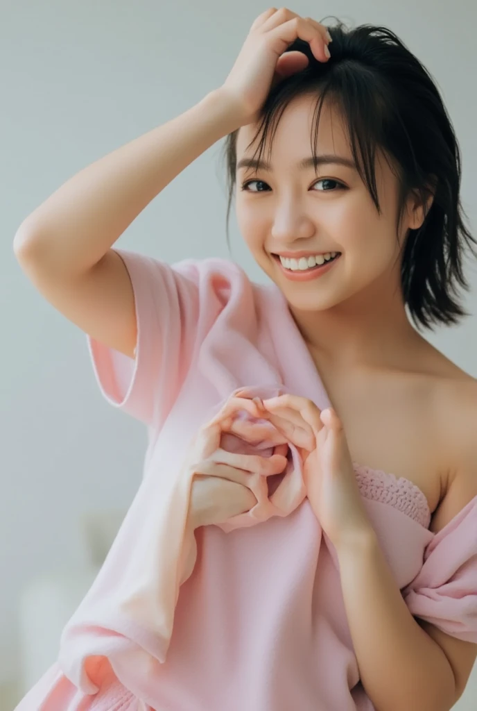 A smiling woman poses alone wearing off-the-shoulder pajamas in pastel colors that convey warmth simply by touching them softly and softly, making a firm, large heart shape with both hands, and holding them in front of her chest, View above collarbone、The background is a monotone 、
