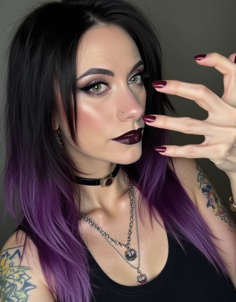 The image shows mghla taking a selfie, styled in a gothic fashion. Her hair is a mix of black and purple, with the colors blending in streaks or sections. She is wearing various pieces of jewelry, such as rings, Choker, or bracelets, but notably has no piercings visible. Her makeup is dark, featuring bold black eyeshadow or eyeliner and possibly dark lipstick, contrasted by white highlights on her face, accentuating certain facial features like the eyes or cheekbones.
