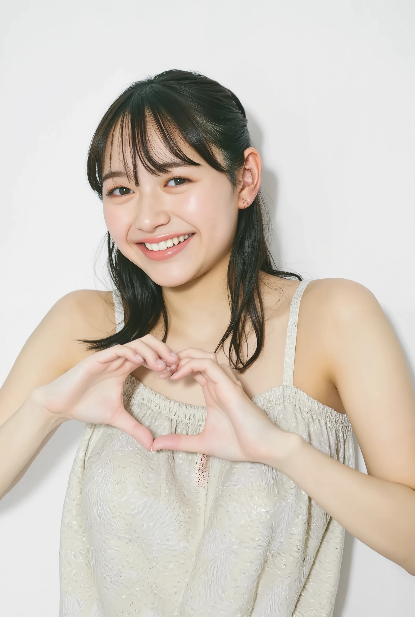 A smiling woman poses alone wearing off-the-shoulder pajamas in pastel colors that convey warmth simply by touching them softly and softly, making a firm, large heart shape with both hands, and holding them in front of her chest, View above collarbone、The background is a monotone 、
