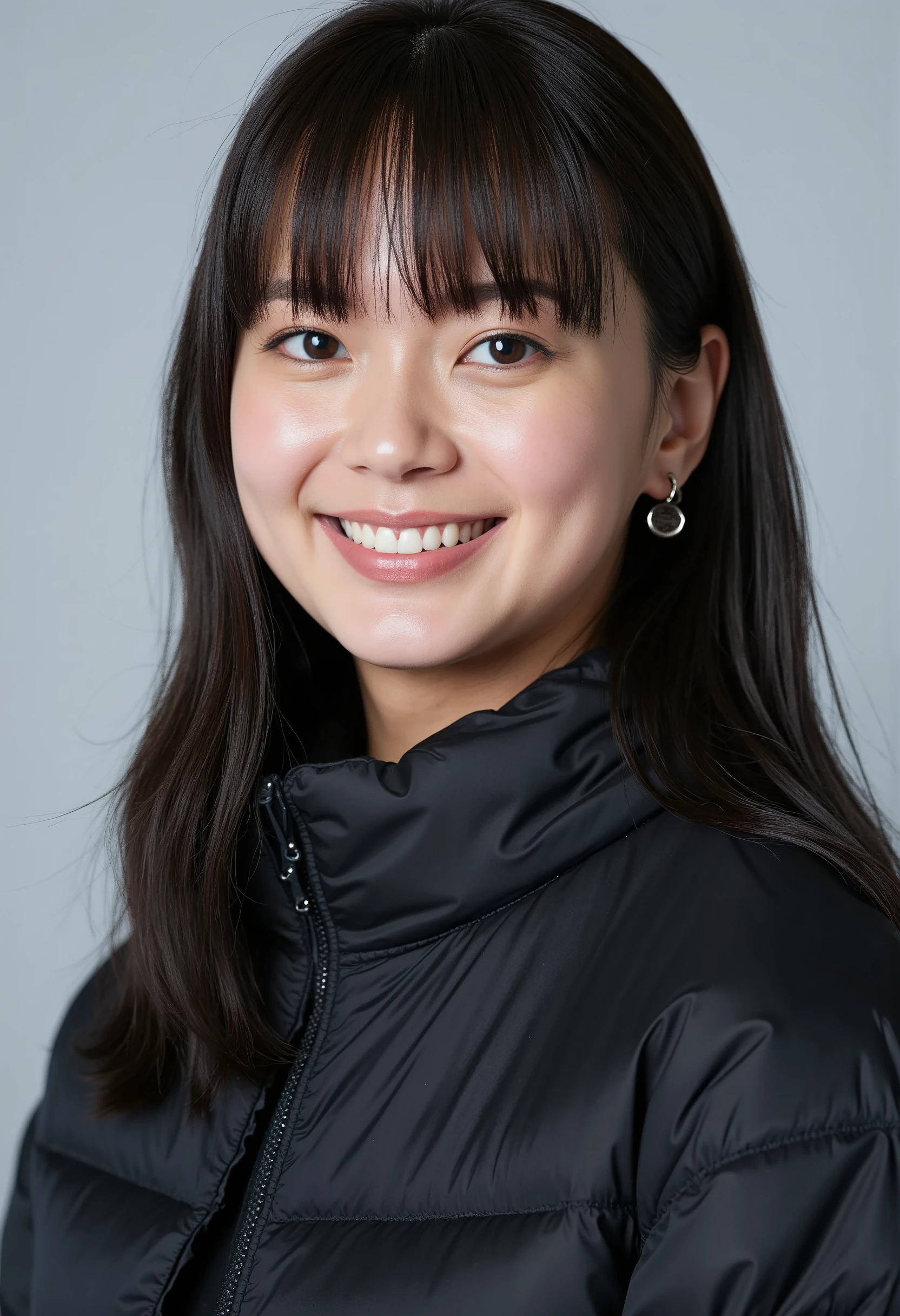 young Japanese woman、 black hair、 ear piercing、smile、 beautiful alignment of teeth、 black down jacket、Gray background