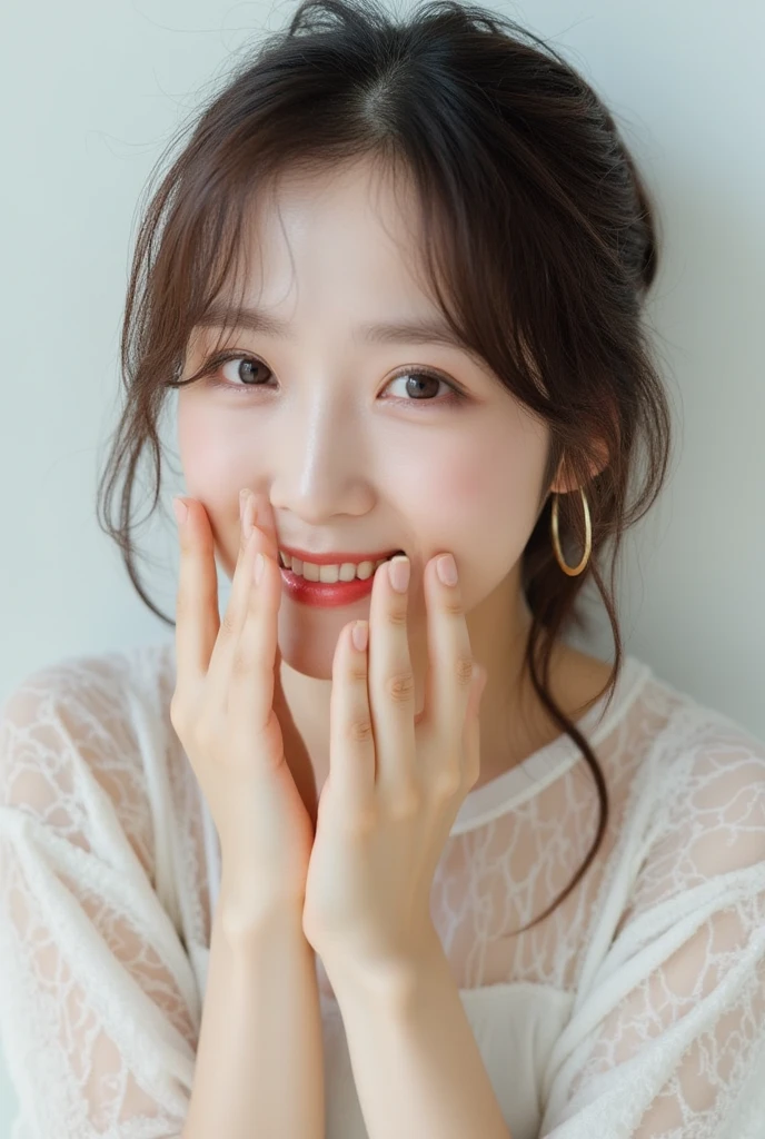 The image is a close-up portrait of a young cute asian woman with shoulder-length brown hair that is messy and unkempt. She is wearing a white top with a sheer, abstract pattern on it. Her face is slightly tilted to the side and she is smiling, with her mouth slightly open and her hands covering her mouth. She has a large gold hoop earring hanging down from her right ear. Her left hand is resting on her face, covering her face with her fingers. She appears to be smiling and looking directly at the camera. The background is a plain white wall, and the overall mood of the image is peaceful and serene.