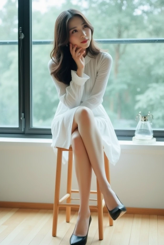 The image shows a young cute asian woman sitting on a wooden stool in front of a large window. She is wearing a white dress with a high neckline and long sleeves. Her hair is styled in loose waves and she is wearing black high heels. The woman is resting her chin on her hand and appears to be deep in thought. The window behind her is made of glass and has a view of trees outside. The floor is made up of light-colored wood planks. The overall mood of the image is peaceful and contemplative.