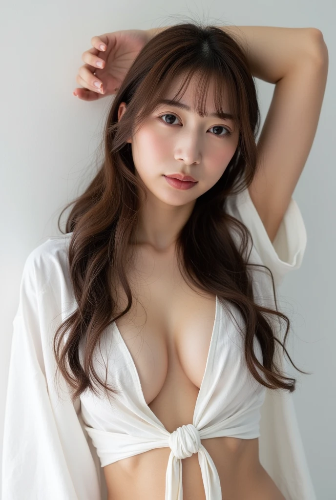 A stunning photo of a young cute asian woman with long hair, long and wavy , clear smooth white skin, is depicted in a seductive manner. The woman's upper body art is clad in a bra, revealing a low-neck top that is tied at the waist, adding a touch of charm to the scene. She is standing in front of a plain white background, with her arm raised for support. Her gaze is full, framing her delicate hair, adding depth to the composition.wearng a oversized shirt. Erotic atmosphere 