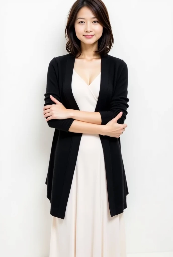 The image is a full-length portrait of a young asian woman standing with her arms crossed over her chest. She is wearing a black shawl over a white dress. The woman has shoulder-length dark hair that is styled in loose waves and falls over her shoulders. She has a neutral expression on her face and is looking directly at the camera. The background is plain white, making the woman the focal point of the image.