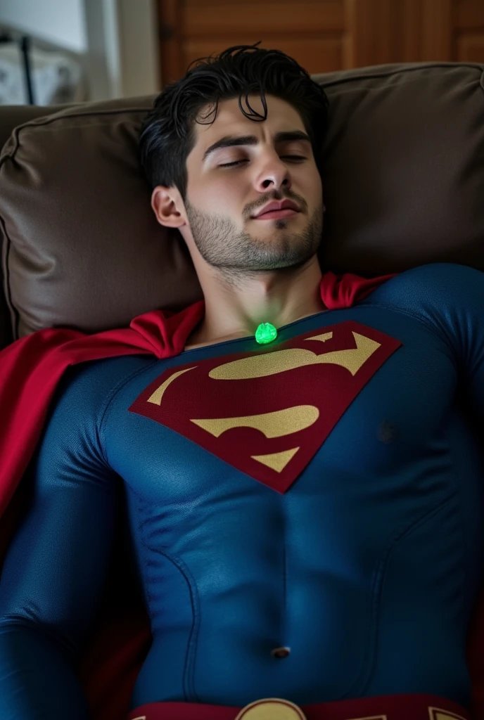 Cody Christian wearing a blue Superman costume, Superman suit, His chest displays the iconic "S" symbol. Superman's traditional red cape is present, attached to the shoulder and flowing behind him, lies on a sofa at home, pained facial expression, almost unconscious, eyes closed, a glowing emerald green crystal pendant hanging around his neck