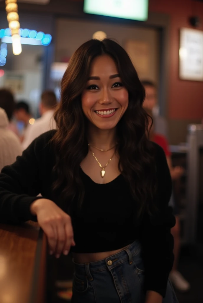 karfuku, siting at the stool of a dimly lit bar.  She has a warm, inviting smile, revealing her straight, white teeth with long, wavy, dark brown hair cascading over her shoulders. She is dressed in a black, tight long-sleeved, knit top, and denim Mid Rise Pleated Skirt. She accessorizes with a gold necklace with a heart pendant. full body, cowboy shot on a Sony Alpha 1 dslr 8k camera. there is a slight bokeh effect and film grain. she is looking at the viewer. Breasts. Pale skin