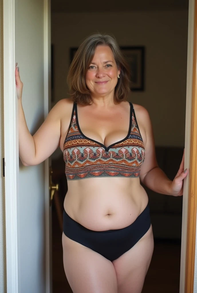 German 51 year old chubby mature woman , with flat stomach and chubby hips , fair skin without makeup, straight short brown hair with gray roots, dominant cheeky look , dressed in a colorful tank top with lots of neckline, tight black hotpan , standing comfortably in the door frame of the living room