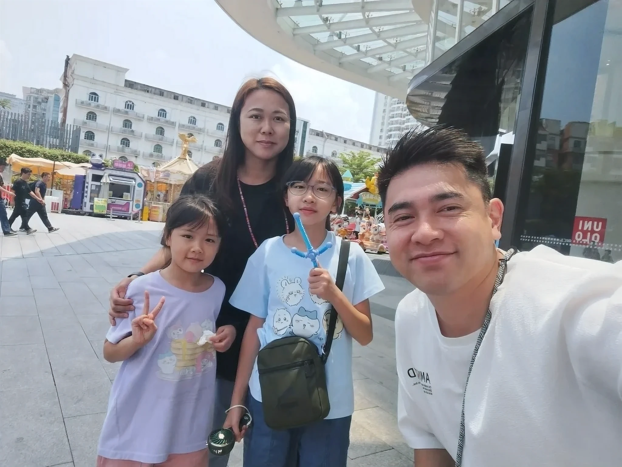 there are three people and a child sitting on a bench, street pic, in city street, in a city square, in front of ramen shop, captured on iphone, standing in a city center, at a city street, 🤬 🤮 💕 🎀, with many travelers, happy family, in a street, taken on iphone 14 pro