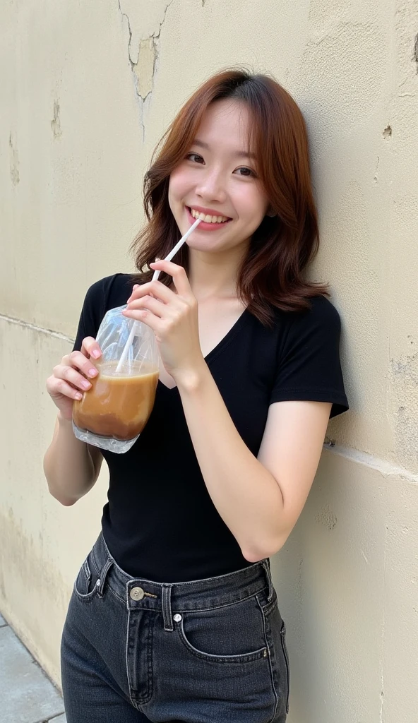 A young woman, likely in her late teens or early twenties, with shoulder-length brown hair, is leaning against a weathered, off-white wall.  She's of East Asian ethnicity with a light complexion.  She wears a simple black, close-fitting, v-neck, short-sleeved top, and dark-wash denim jeans. Her expression is joyful and happy, actively involved in drinking from a plastic bag containing a brown beverage through a straw. Her hands are in the act of holding the bag and straw.  The wall behind her is heavily textured, with noticeable cracks and a slightly rough surface.  The lighting is natural and soft, casting no harsh shadows. Ambient light is diffused, highlighting the textures of the subject and the wall. The overall style is candid, and the mood is cheerful and relaxed, typical of casual, street-style photography. The image appears to be shot from a slightly low angle, focusing on the subject.  The color palette is predominantly neutral and earthy tones with a focal contrast presented by the drink inside the bag and the subject's clothing.  The bag and surrounding elements exhibit subtle, soft texture.  The image conveys a relaxed and casual feeling.