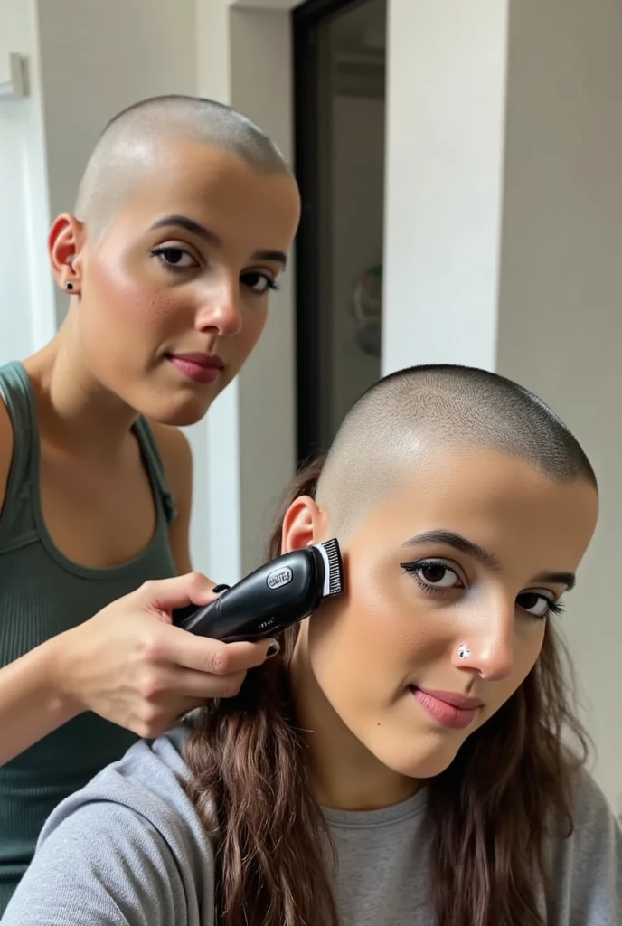 Real photograph of two thin beautiful young women, one shaving the other's head. ((((first woman is hairless, bald smooth pale skin on her head)))), (((she is holding "Wahl" hair clippers which are currently (shaving the second woman's head), she is intensely looking at the (second woman's bald head and hair clipper)))). The (((second woman has her top and left side of her head completely bald))). ((she is excitedly looking at the viewer and smiling)). (((There are clumps of hair and long strands of cut hair stuck on and draped over her shirt))).
