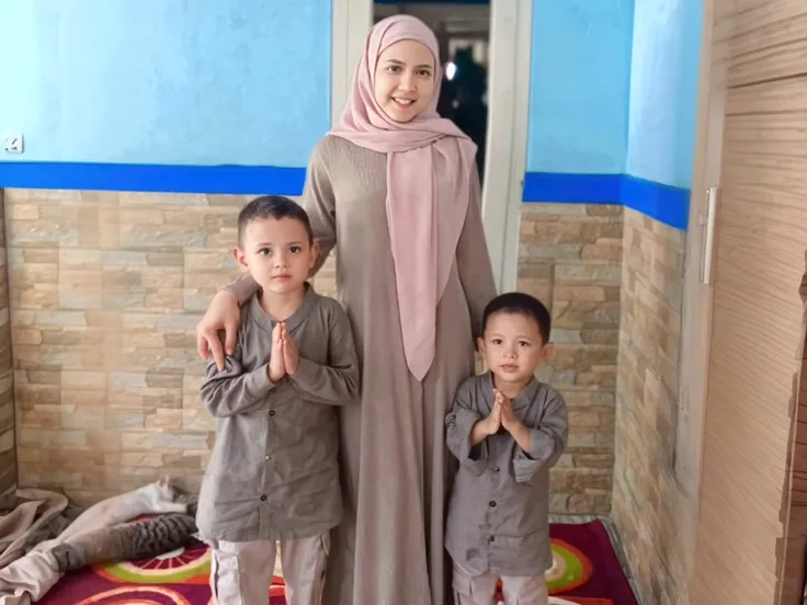 foto keluarga indonesia, empat anggota, satu ayah usia 35 tahun, satu ibu usia 33 tahun, satu anak perempuan usia 10 tahun dan satu anak laki-laki usia 2 tahun. mereka kompak memakai baju muslim khas melayu warna cokelat mewah dan gamis sharia warna yang sama dan selaras, foto studio, ruang tamu cerah, pencahayaan siang, dinding dengan seni grafiti bertuliskan selamat lebaran idul Fitri, seni Doodle ketupat, bulan bintang, realistik.