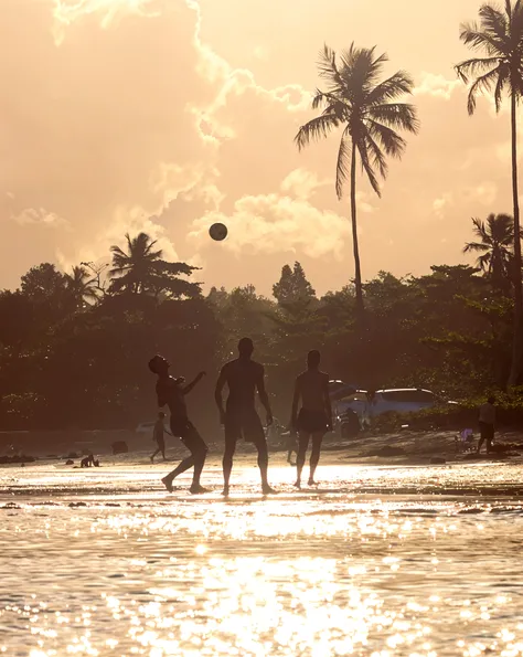 a group of children playing in the beautiful beaches of Nicaragua, sandy beaches with crystal clear turquoise waters, a girl surfing the waves, a boy building a sandcastle, kids running and laughing, colorful umbrellas and beach towels, palm trees swaying in the breeze, vibrant beach atmosphere, sunset casting a warm golden glow over the scene, highres, vivid colors, beach vacation, joyful moments