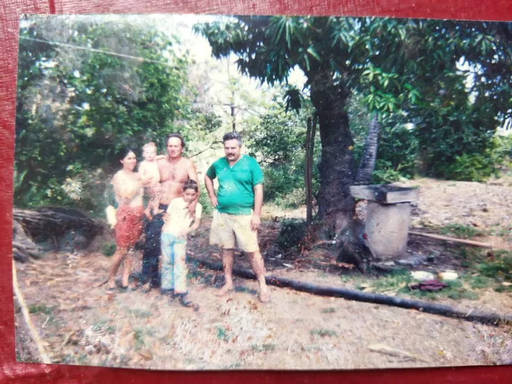 There are two small children next to a man in a yellow shirt, old color photo, old color photograph, taken in the early 1960s, taken in the 1970s, northeastern people in Brazil, taken in the early 1970s, taken in the late 1970s, 1 9 7 0 Color photography
