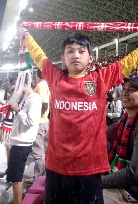 4D caricature of a 10 year old Indonesian boy, front view running happily chasing his dreams like a champion, his right hand clenched upwards and on his arm is a red and white ribbon. Indonesia is wearing a red t-shirt that says "DAFFA" and white pants and black shoes holding the Indonesian flag. in a complete circle with a sharp bamboo background of Indonesian independence.
Realistic Full HD 12K is very clear and super detailed.