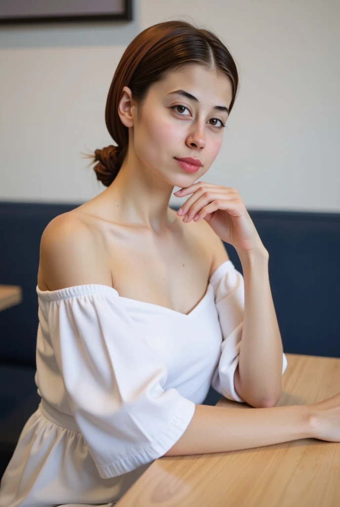 A young woman with blue eyes and dark brown hair in a loose updo, wearing an off-the-shoulder white top, sitting at a table, leaning forward, with one hand touching her chin, soft contemplative expression, dark blurred background
